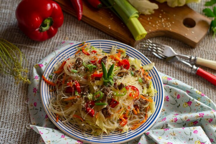 A bowl of beef and vegetable stir-fry, garnished with sesame seeds and fresh herbs.