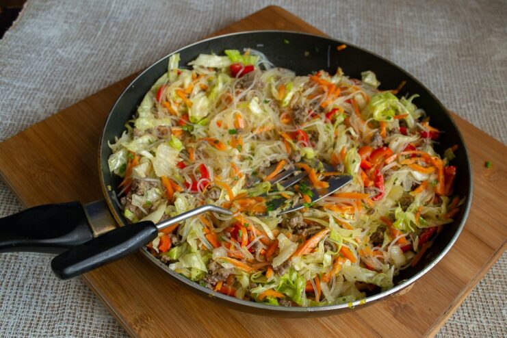 Soy sauce being poured over the finished stir-fry in the pan before mixing.