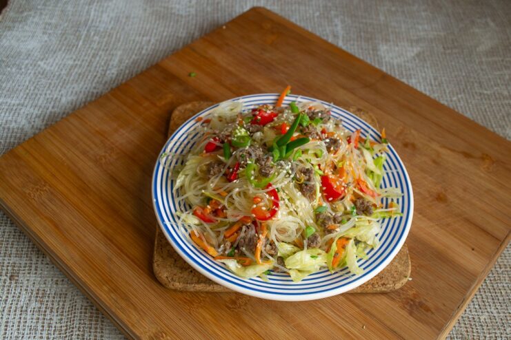 A close-up of the finished beef stir-fry in a bowl, garnished with white sesame seeds.