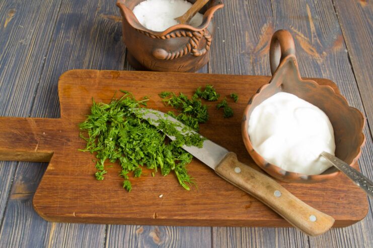 Making the Creamy Dill Sauce Fresh dill being chopped and mixed with smetana (sour cream) to make a creamy sauce.