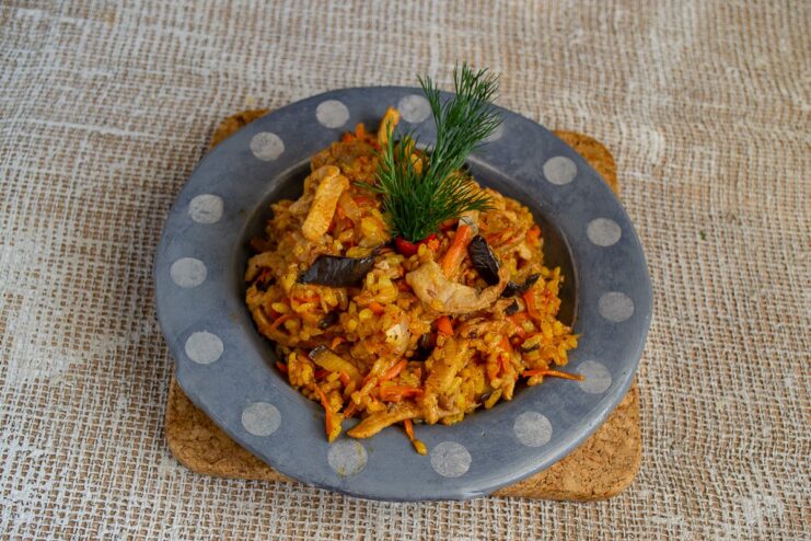 Serving the Spicy Pork Stew with Fresh Herbs and Sesame Seeds A serving of the spicy pork and eggplant stew in a white bowl, garnished with dill and sesame seeds.