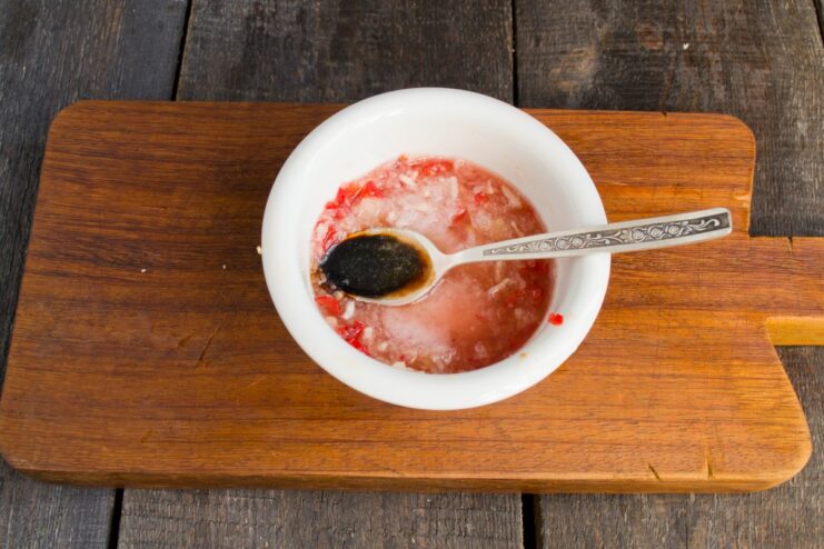 Mixing the aromatic marinade with soy sauce, honey, and spices. A bowl with marinade ingredients like soy sauce, grated ginger, and onion being mixed.