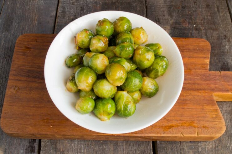 Tossing the Brussels sprouts in the flavorful pan drippings. Boiled Brussels sprouts being warmed in the same skillet used for the pork.