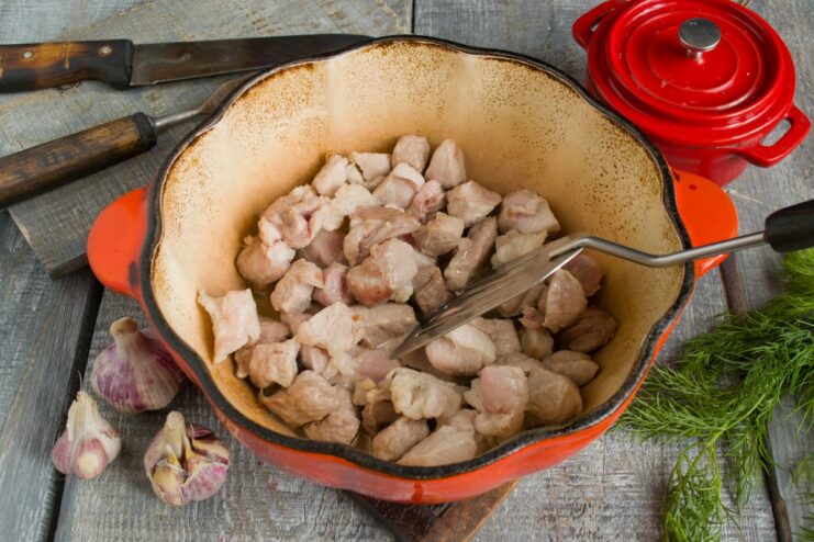 Searing Pork Pieces to Lock in Flavor for the Stew Pieces of pork being fried in a pan with hot vegetable oil.