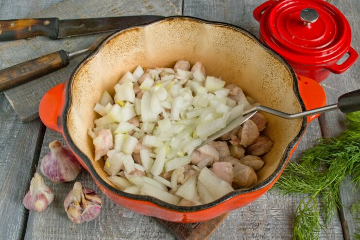 Sautéing Onions with Pork to Build a Flavorful Base Finely chopped onions being added to the pan with frying pork.