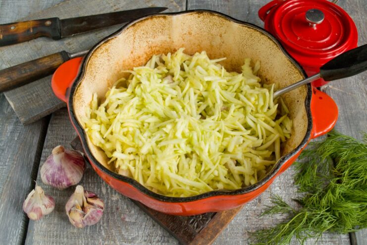 The Secret to a Thick Gravy: Adding Grated Zucchini Grated zucchini being added to the pot with pork and other vegetables.