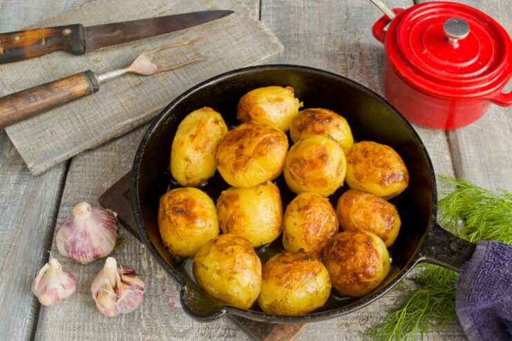 Preparing the Perfect Side: Golden-Fried New Potatoes Boiled new potatoes being fried in a pan with butter until golden brown.