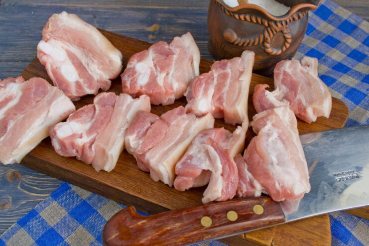 Tenderizing Pork with a Knife for a Softer Texture A hand using the back of a knife to lightly tenderize a piece of pork.