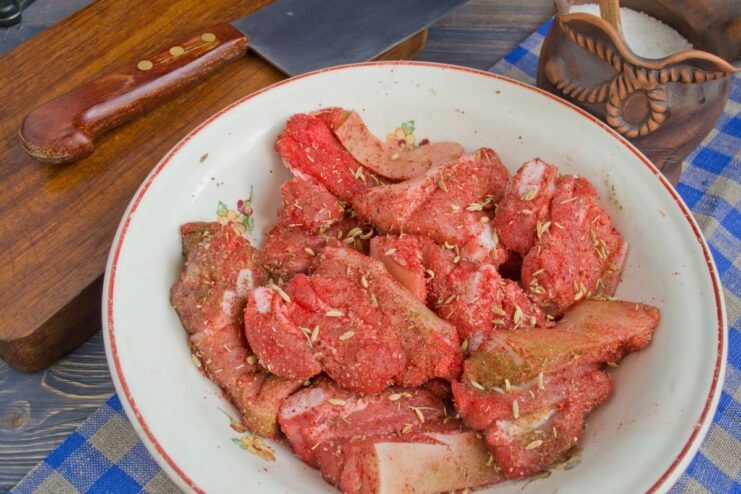 Seasoning Pork with Spices Before Baking Pieces of raw pork being seasoned with salt, pepper, and caraway seeds.