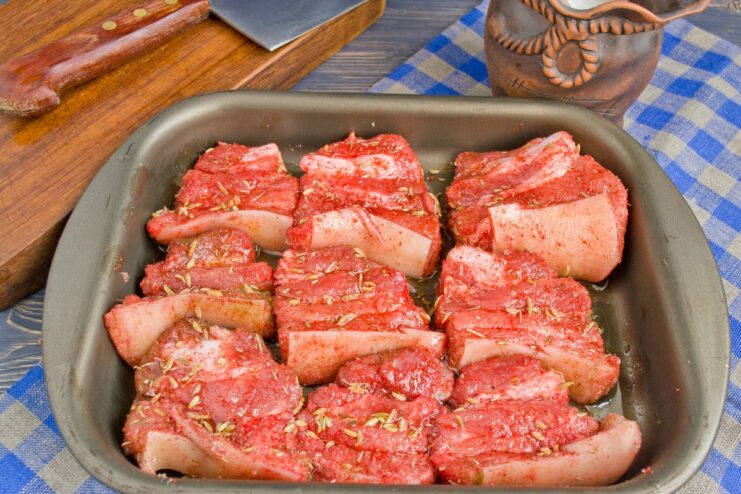 Arranging Seasoned Pork in a Baking Dish Seasoned pork pieces arranged in a single layer in a glass baking dish.