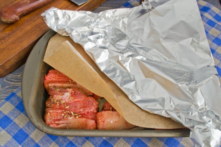 Baking Pork Covered with Parchment and Foil A baking dish covered with parchment paper and aluminum foil, ready for the oven.