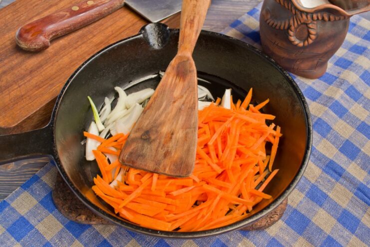 Sautéing Onions and Carrots for the Vegetable Base Chopped onions and julienned carrots being sautéed in a frying pan.