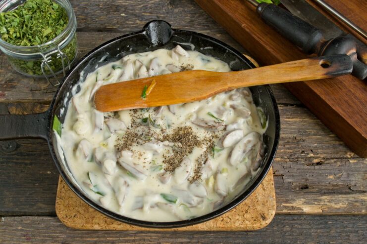 Seasoning the Dish to Perfection Hand sprinkling freshly ground black pepper into the skillet with pork kidneys and gravy.