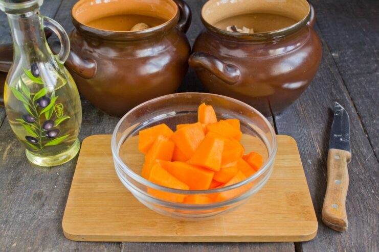 Sweet and Savory: Adding a Layer of Diced Pumpkin Diced bright orange pumpkin layered over mushrooms in the clay pots.