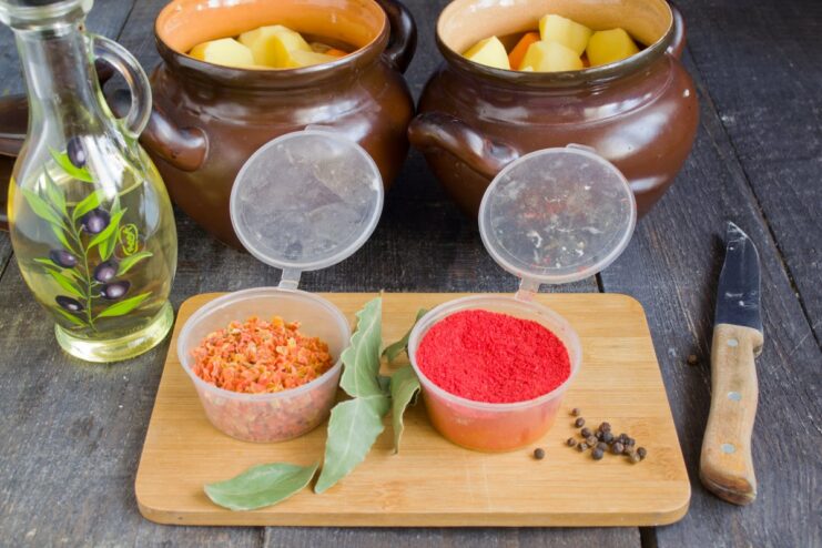 Seasoning to Perfection: Adding Spices for a Rich Aroma Spices, including bay leaves and peppercorns, sprinkled over the layered ingredients in the clay pots.