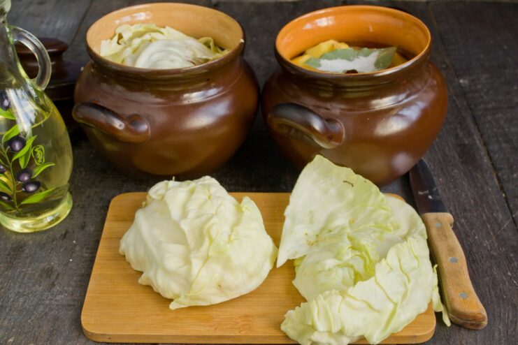 A Natural Lid: Using Cabbage Leaves to Keep Everything Moist The ingredients in the clay pots are covered with large white cabbage leaves before baking.