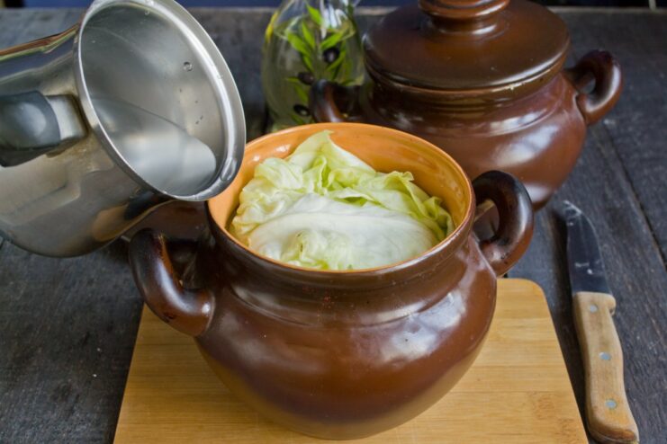 Adding Liquid for a Juicy and Tender Result Pouring water or broth into the clay pots over the layered ingredients.