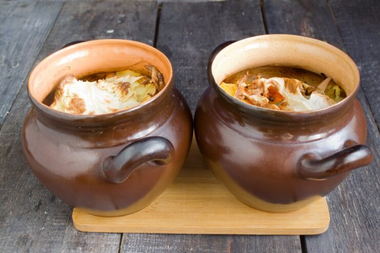 Slow-Baking in the Oven for Fall-Off-The-Bone Ribs Two clay pots with lids on, placed inside an oven to bake.