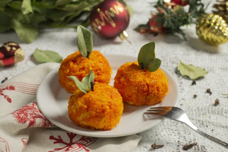 A plate of festive cheese appetizers 'Mandarinki', shaped like tangerines and garnished with bay leaves.
