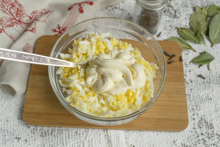 Binding the Ingredients with Mayonnaise Mayonnaise being squeezed from a pouch into the bowl with the cheese and egg mixture.