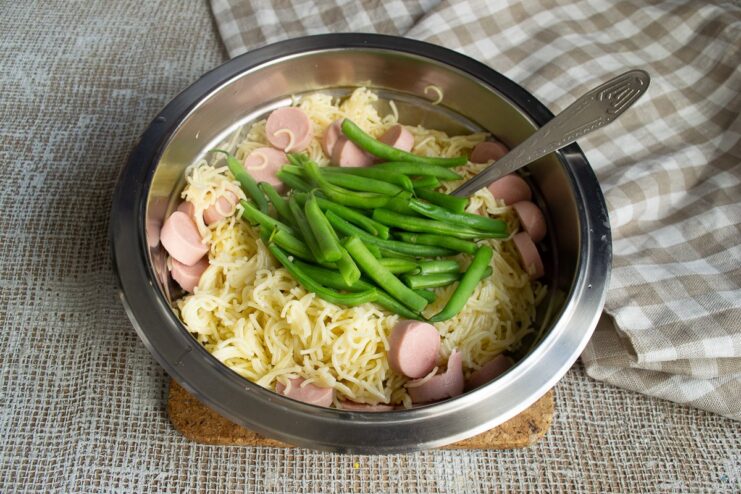 Blanching green beans to keep them crisp and vibrant. Adding blanched green beans to the bowl with vermicelli and sausages.