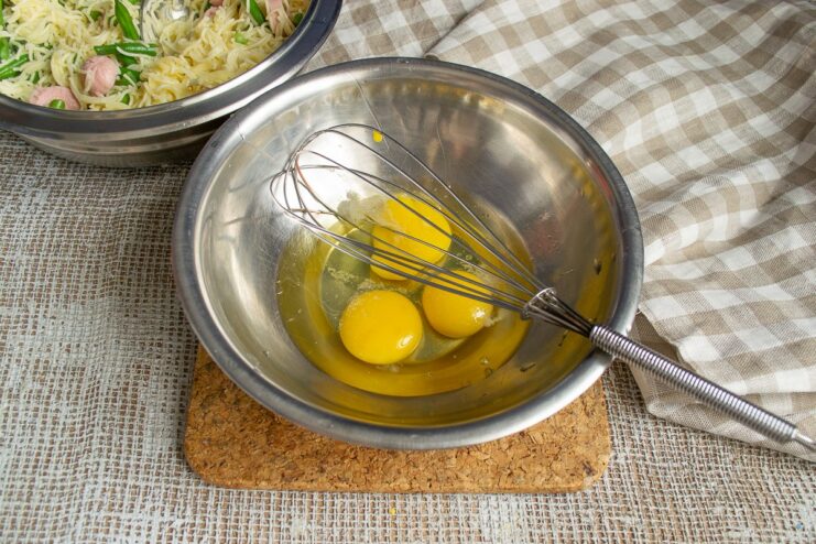 Preparing the egg mixture for the casserole. Whisking eggs in a clear glass bowl.