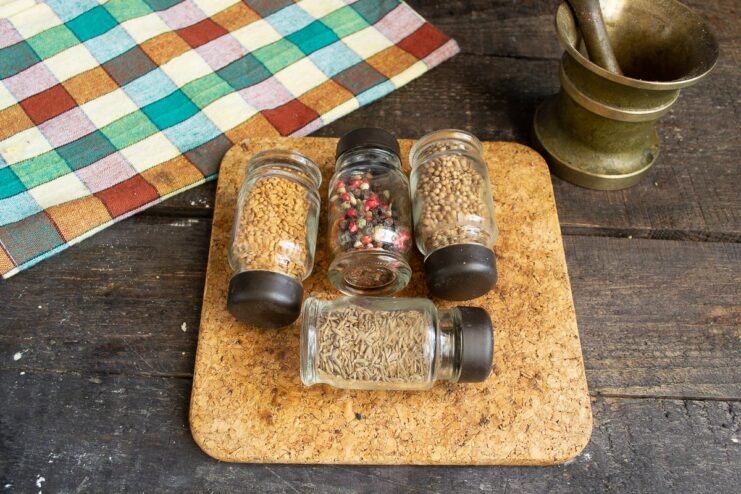 Grinding your own spices releases their maximum aroma and flavor. Whole spices like cumin and coriander being ground in a mortar and pestle.