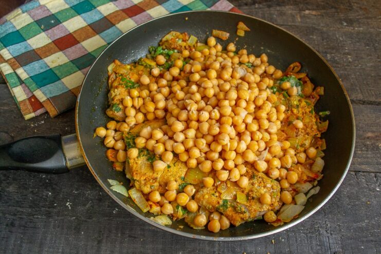 Simmering all the ingredients together allows the flavors to meld beautifully. Chickpeas and lime juice being added to the meat curry in the pan before simmering.