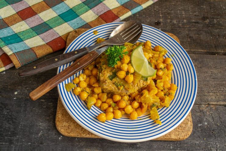 A final squeeze of lime juice brightens up all the flavors of the curry. A serving of hot chickpea curry in a bowl, with a lime wedge on the side.