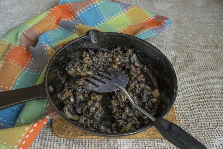 Sautéing chopped mushrooms and onions until golden to add a deep umami flavor. Chopped mushrooms and onions being sautéed in a hot skillet.