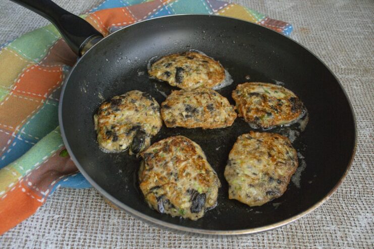 Frying the zucchini fritters in a skillet until they are perfectly golden and crispy. Zucchini fritters cooking in a non-stick skillet, turning golden brown.