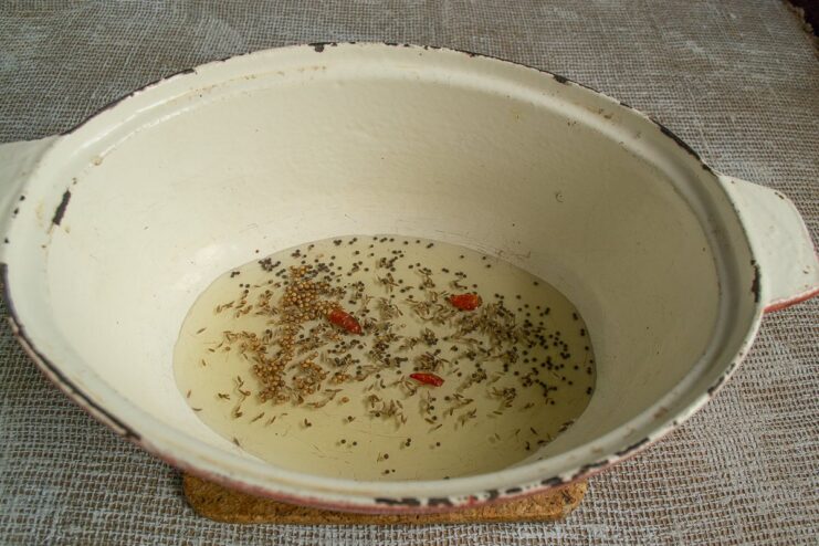 Blooming Spices in Hot Oil for Maximum Flavor A mix of whole spices like cumin and coriander seeds toasting in hot oil in a pan.
