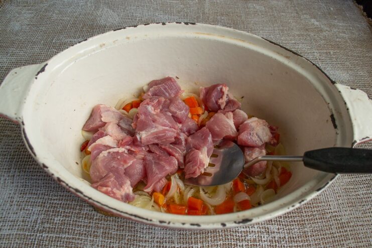 Searing Pork Pieces to Lock in Juices and Flavor Cubes of pork being seared in a pan with onions and carrots.