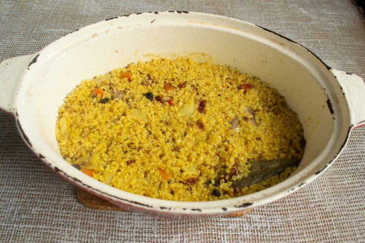 Simmering the Plov to Perfection with Garlic and Water A whole head of garlic placed in the center of the bulgur plov before simmering.