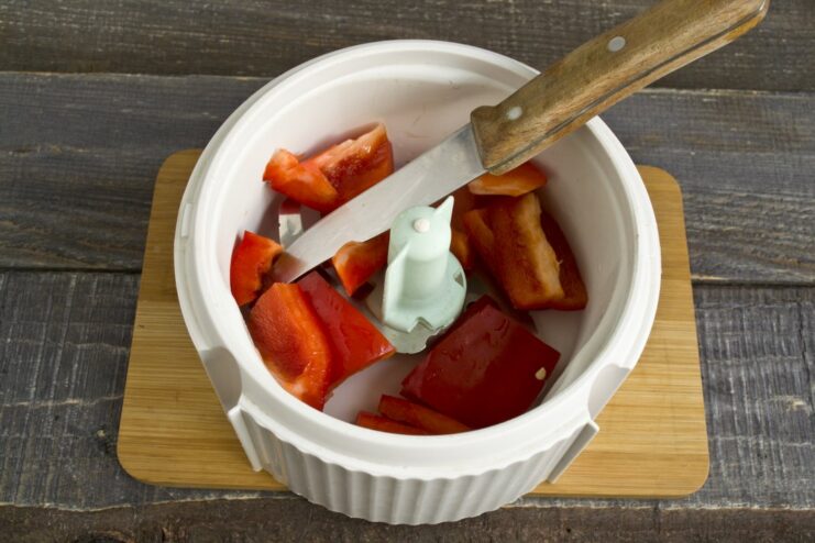 Step 1: Preparing sweet peppers for the rich Tefteli sauce. Sliced red bell peppers in a transparent blender bowl, ready for making the sauce.