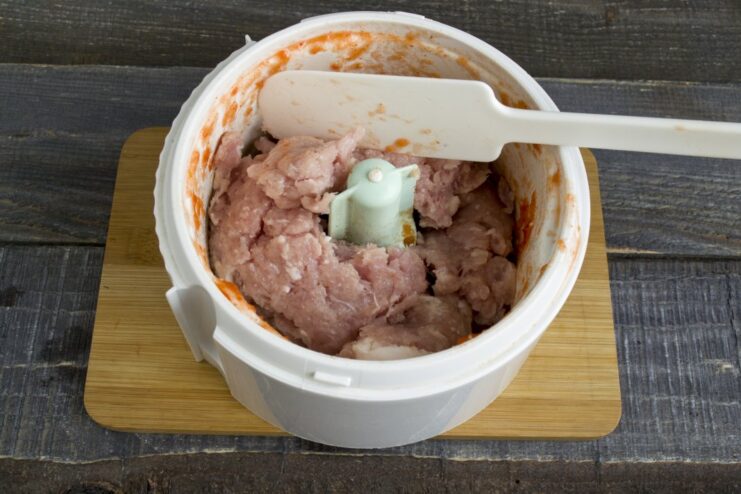 Preparing the meatball mixture: starting with ground pork in the blender. A portion of fresh ground pork inside a clean blender bowl.