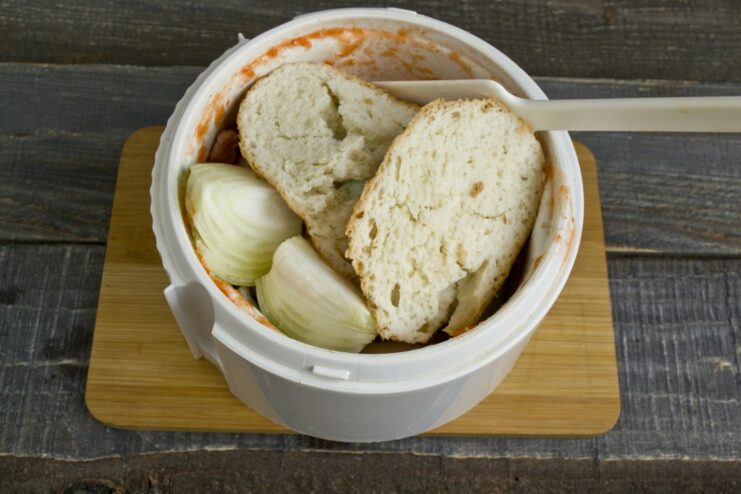 The secret to tender meatballs: adding milk-soaked bread to the mixture. Pieces of white bread soaked in milk being added to the ground pork and onion in the blender.