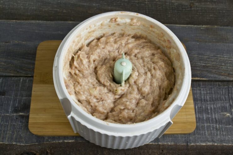 Blending the pork, onion, bread, and spices into a smooth meatball mixture. Spices sprinkled over the meatball ingredients in the blender before mixing.