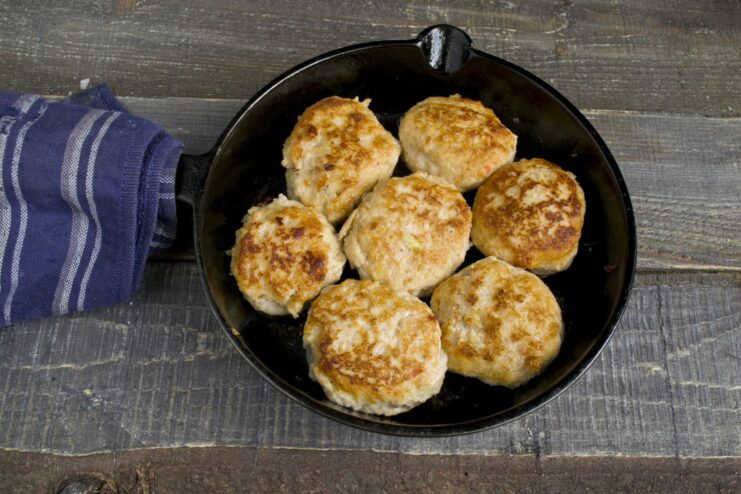 Frying the meatballs until they are perfectly golden brown on all sides. Round pork meatballs being fried to a golden-brown crust in a hot frying pan.