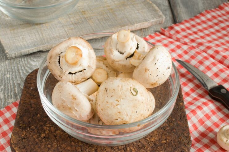 Preparing the Mushrooms - Clean and Ready to Cook Whole fresh champignon mushrooms being washed and dried.
