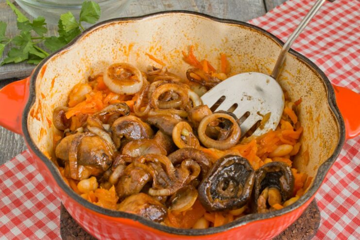 Simmering the Stew to Meld All the Flavors The bean and mushroom stew simmering in a pot with a wooden spoon.
