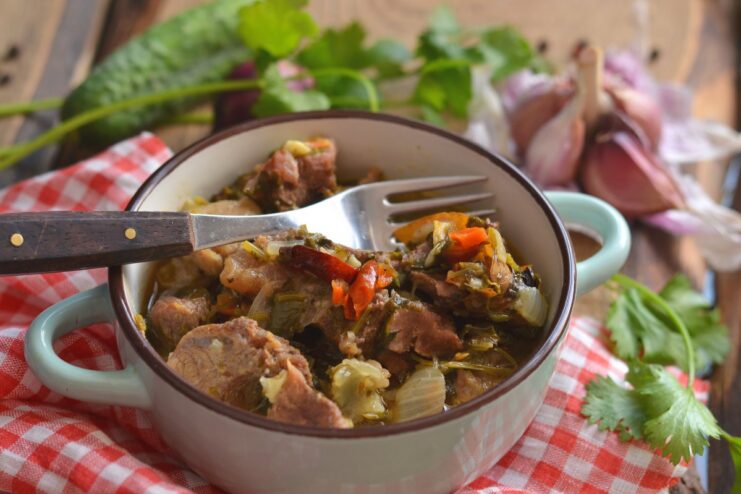 A plate of braised pork in a rich white wine sauce, garnished with fresh herbs.