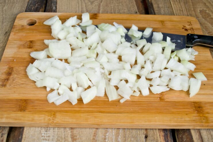 Finely Chopping Yellow Onions for the Stew Base A pile of finely chopped yellow onions on a cutting board.