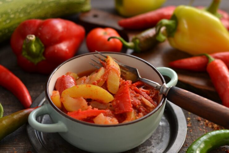 A bowl of stewed zucchini with tomatoes and peppers, garnished with fresh herbs.