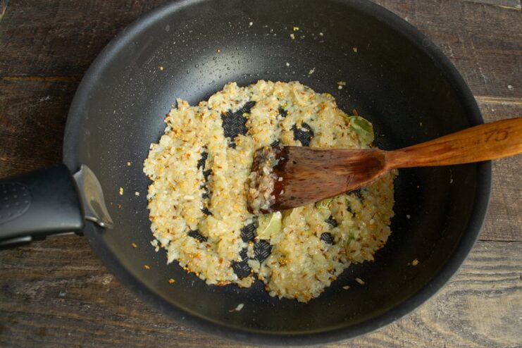 Cooking onions until golden and caramelized to build flavor Onions and spices sautéing in a skillet, turning a light golden brown.