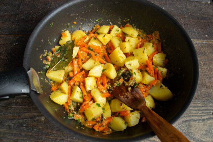 Reducing the liquid to thicken the stew after the initial cooking Stewed potatoes and vegetables simmering in a skillet with the lid off.