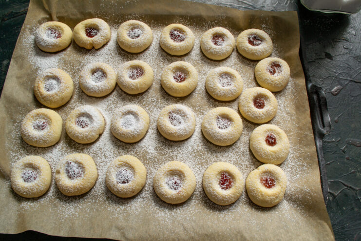 Dusting the warm cookies with powdered sugar Dusting freshly baked vanilla cherry cookies with powdered sugar using a small sieve.
