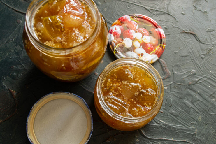 Step 8: Canning the hot jam into sterilized jars. Pouring hot apple and physalis jam from a pot into a sterilized glass jar.