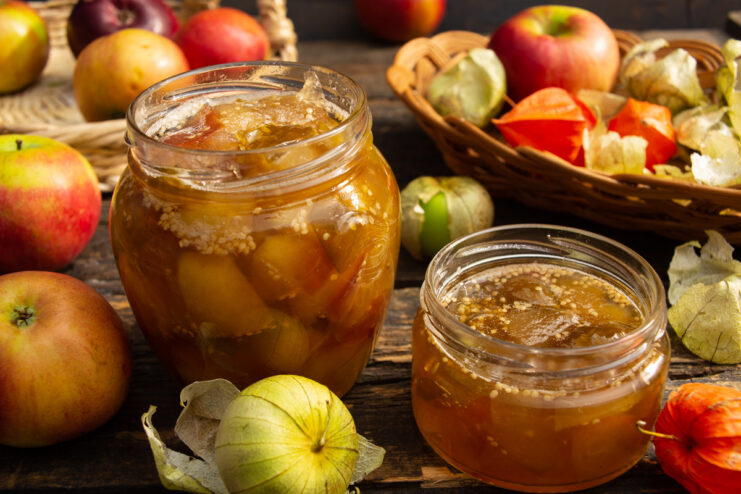 A glass jar filled with golden Apple and Physalis Jam, sealed with a lid.
