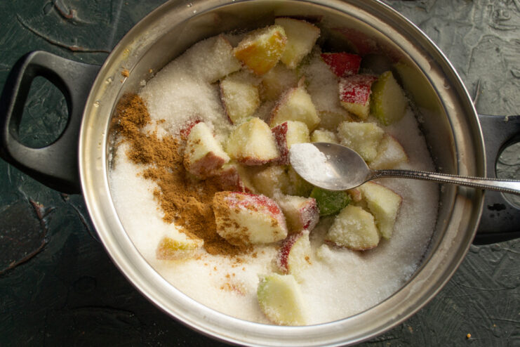 Step 5: Flavoring the jam with cinnamon and vanilla. Adding ground cinnamon and vanillin powder to the fruit mixture in a pot.